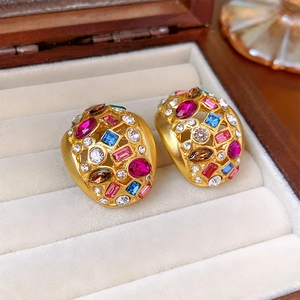 Close-up of vintage gold earrings with colorful round, square, and oval gemstones