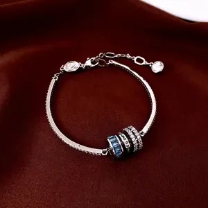 Silver necklace with blue stone bead and swan clasp on red velvet background