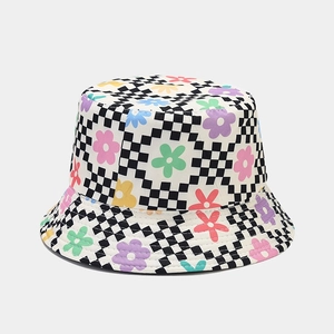 Détail d'un chapeau bob avec fleurs colorées sur motif de damier noir et blanc