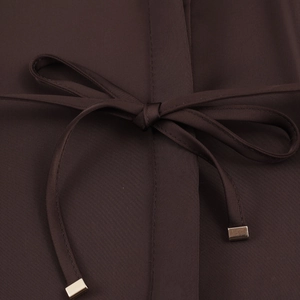Detail of satin blouse with a waist tie featuring square metal tips on dark brown fabric