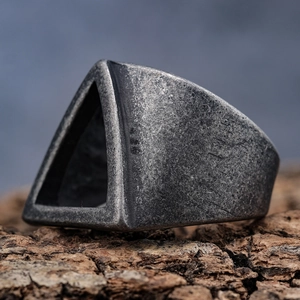Gros plan détaillé d'une bague triangle en argent vintage sur une écorce naturelle
