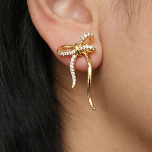Elegant 18k gold plated brass bow earrings with sparkling white cubic zirconia on model