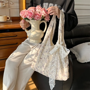 Lace shoulder bag with floral pattern and large bow detail shown in indoor scene