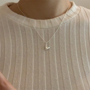 Close-up of a 925 silver L-letter pendant necklace worn on a model's neck