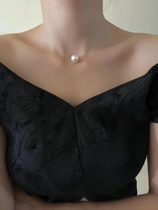 Close-up of a minimalist round pearl pendant on a transparent invisible fishing line chain