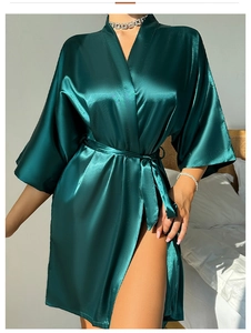 Détail d'un peignoir en satin vert foncé montrant la texture soyeuse et la ceinture