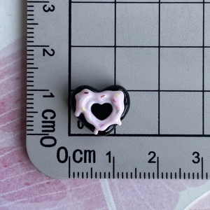 Detailed size measurement of black and pink heart resin charm on a metric scale mat