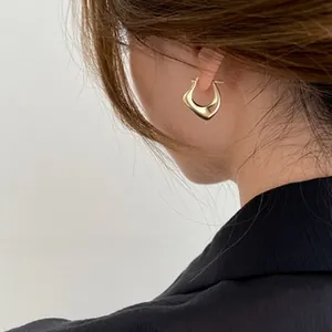 Detail of minimalist gold U-shape geometric earring with polished mirror finish