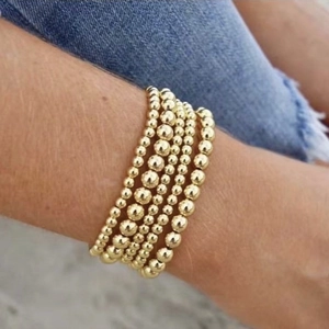 Minimalist stackable gold bead bracelet set on wrist with trendy stainless steel spheres