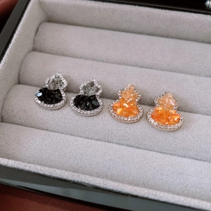 Macro view of gourd-shaped stud earrings in black and orange with crystal accents