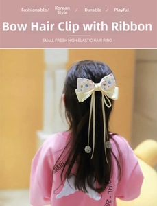 Detail of colorful polka dot bow hair clip with long ribbons on girl's hairstyle