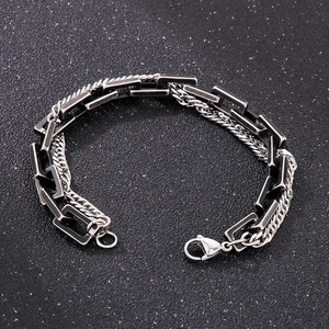 Detail of a double-layered metal bracelet with black square links and silver woven chain