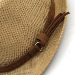 Detail of fine straw weave and brown suede band with golden buckle on a fedora