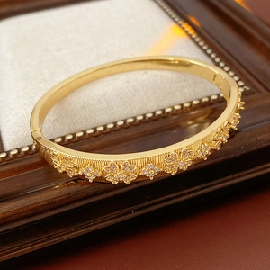 Close-up of gold-plated bangle with hollow floral patterns and zircon accents