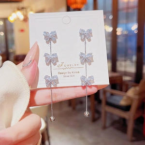 Detail of silver 925 bowknot tassel earrings with sparkling crystals held in hand