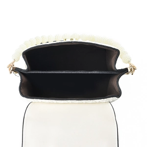 White textured handbag with pearl handle and interior compartments shown from a top view