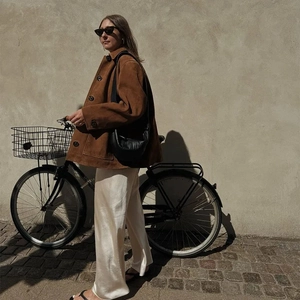 Détail de la veste vintage en daim marron avec pantalon en satin dans un décor de rue
