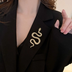 Luxurious gold snake-shaped brooch with scaly texture on a black blazer lapel
