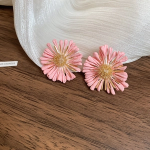 Détail de boucles d'oreilles marguerites en raphia rose avec étamines dorées et fleurs 3D