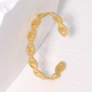 Dettaglio di un bracciale in acciaio dorato con motivo a occhio e bordi perlati