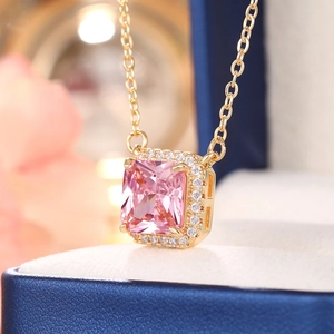 Close-up of golden necklace with square pink gemstone and sparkling diamond halo