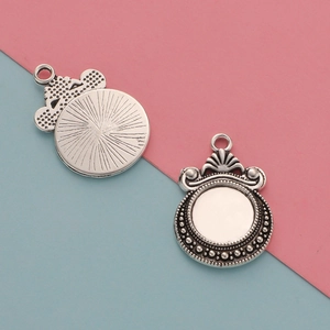 Macro shot of 12mm silver scale pendant charms with decorative border and textured back