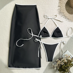 Flat lay of three-piece bikini set with wrap skirt and stylish white piping detail