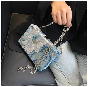 Detail of floral jacquard fabric and silver chain strap on a vintage square handbag