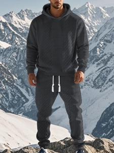 Detail of grey men's waffle knit tracksuit set featuring hoodie and joggers in snowy mountains