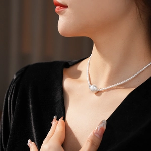 Dettaglio di elegante collana di perle con grande ciondolo rotondo su velluto nero