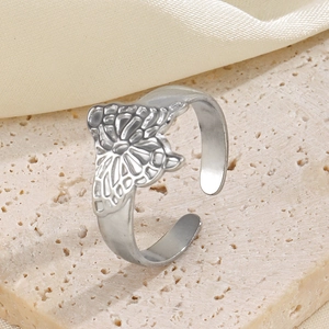 Adjustable stainless steel butterfly ring on a beige stone with silk background