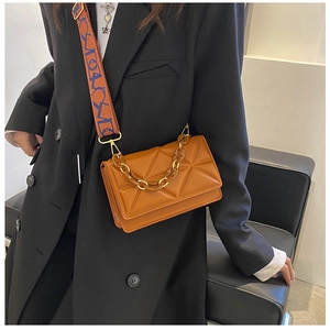 Detail of orange crossbody bag featuring geometric quilting and stylish amber acrylic chain