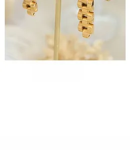 Macro detail of the 18k gold plated watchband chain style earrings with polished finish