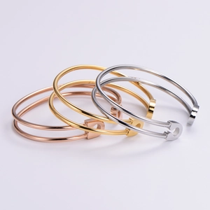 Three minimalist stainless steel safety pin bracelets in rose gold, gold, and silver finishes