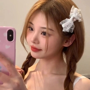 White lace bow hair clip with heart detail worn by a woman in a mirror selfie