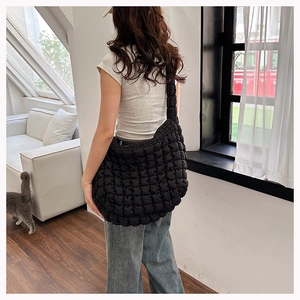 Detail of a black quilted cloud tote bag with puffer texture on a female model