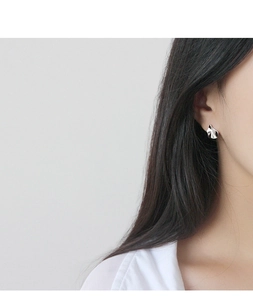 Vue détaillée d'une boucle d'oreille irrégulière plissée en argent sur l'oreille