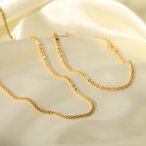 Macro shot of 18K gold plated stainless steel fine chain necklace on silk background