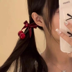 Elegant red velvet cherry bow hair clip accessory worn on a side ponytail hairstyle