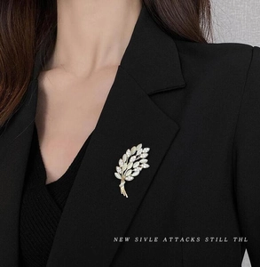 Golden wheat leaf brooch with white stones shown on a black suit jacket lapel