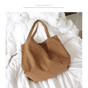 Top view of a brown vintage canvas tote bag on white textured bedding sheets