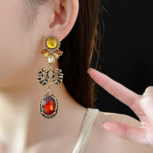 Detailed close-up of vintage bronze bow earrings with red and yellow crystal drops