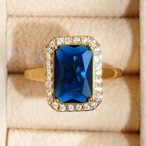 Detailed macro shot of a gold ring with a rectangular sapphire and diamond halo