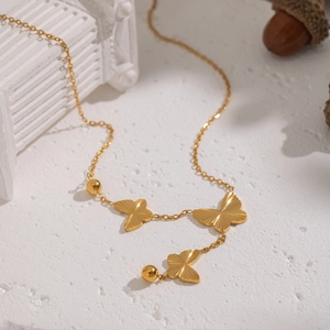 Elegant gold butterfly necklace with three pendants on white textured background