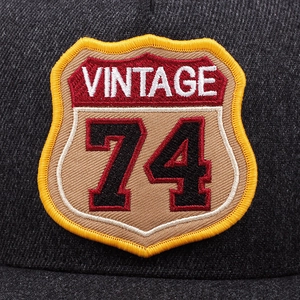 Macro shot of vintage shield embroidery with 74 and VINTAGE text on a mesh trucker hat