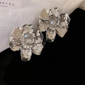 Macro detail of silver metal flower earrings with irregular pleated and hammered texture