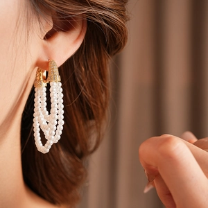Macro detail of vintage gold pearl earrings with zircon stones worn by a model