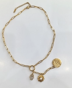 Detail of gold paperclip chain necklace with Hamsa hand and evil eye charms on white background