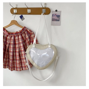 Beige heart-shaped clear bag hanging on a wooden hook with a red plaid skirt