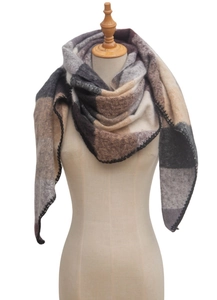 Detailed close-up of plaid triangle scarf texture with soft fringe trim and neutral tones